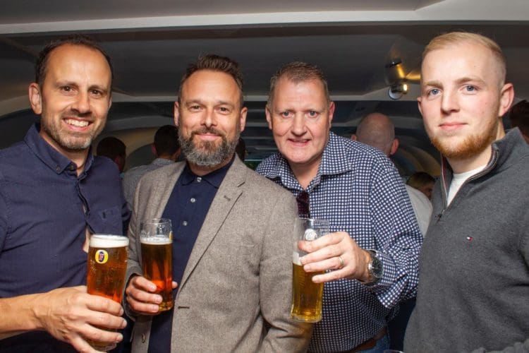 staff members of fit out company rap interiors posing with pints of lager