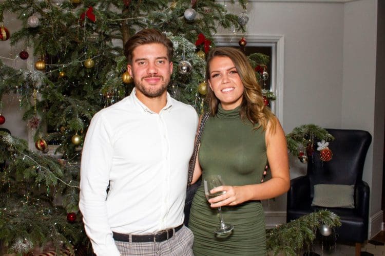 A couple posing for a photograph in front of a Christmas tree at The Yarrow hotel