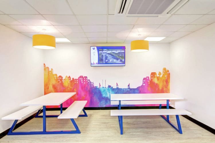 a breakout area with a skyline wall graphic and dining furniture