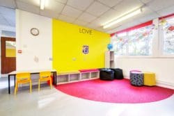 a completed school refurbishment with a reading area and a yellow wall with printed school logo