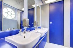 a completed school washroom refurbishment with royal blue panels and tissue dispenser