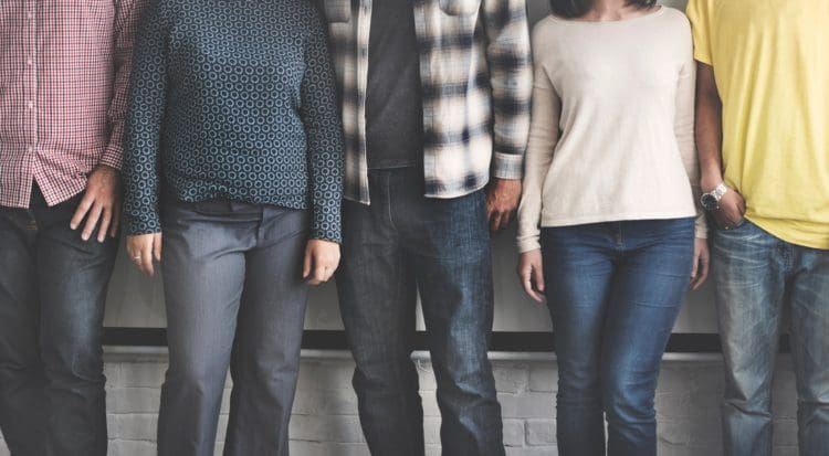 A group of adults standing against a wall