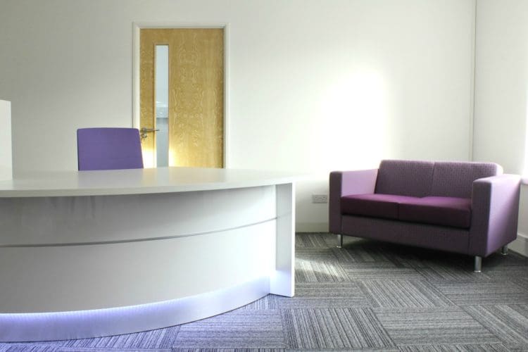office reception area design with purple chairs and a desk