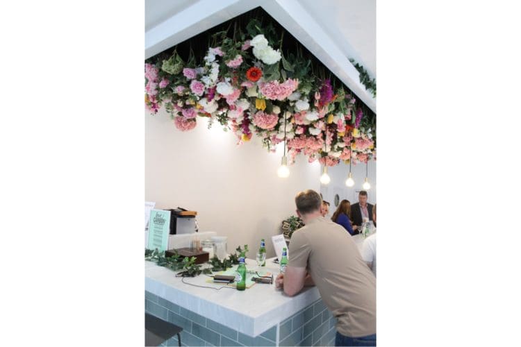 A biophilic office interior design with a hanging floral ceiling display