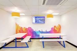 a breakout area with a skyline wall graphic and dining furniture