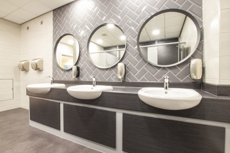 refurbished toilets with metro herringbone tiles and round mirrors