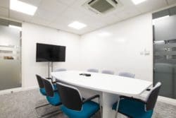 Glass office meeting room with a boardroom table and chairs