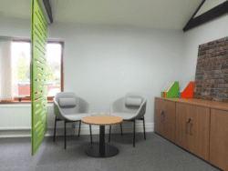 An informal meeting space behind an acoustic screen with storage furniture