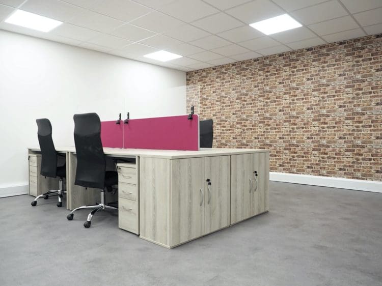 Banks of desks with accompanied task chairs in an open plan office space