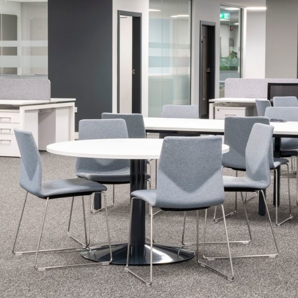 A circular round meeting table with a white top and black base to sit up to 5 meeting chairs around it.