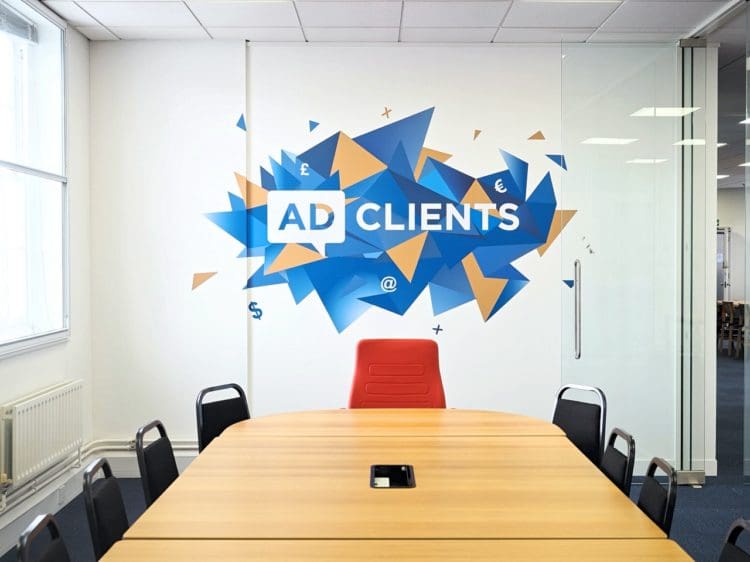 AD Clients large branding logo displayed on the white wall of their office meeting room as an eye-catching feature