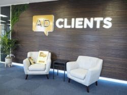 AD clients feature wall with wood veneer panels, light up signage, moss wall design and soft seating area