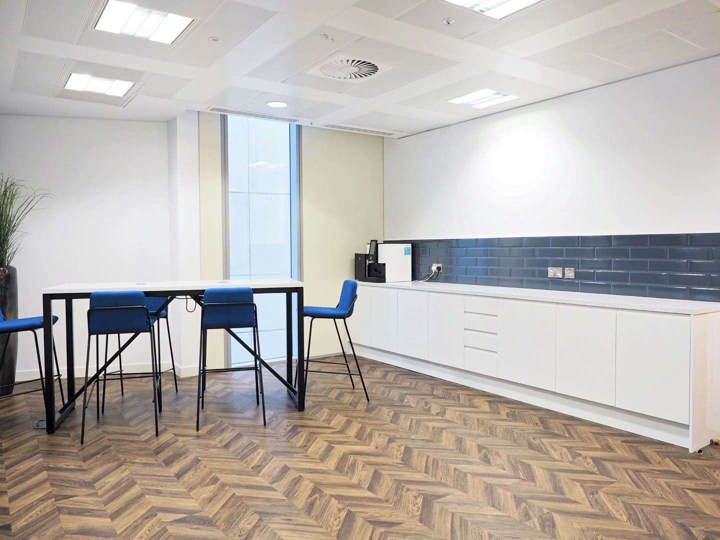 Office breakout area with a shared desk and tiled splashback