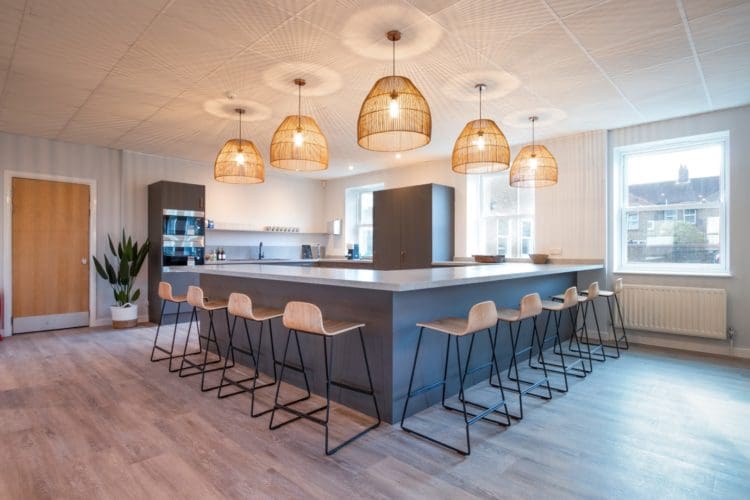 Office kitchen area design with breakfast bar and pendant lights
