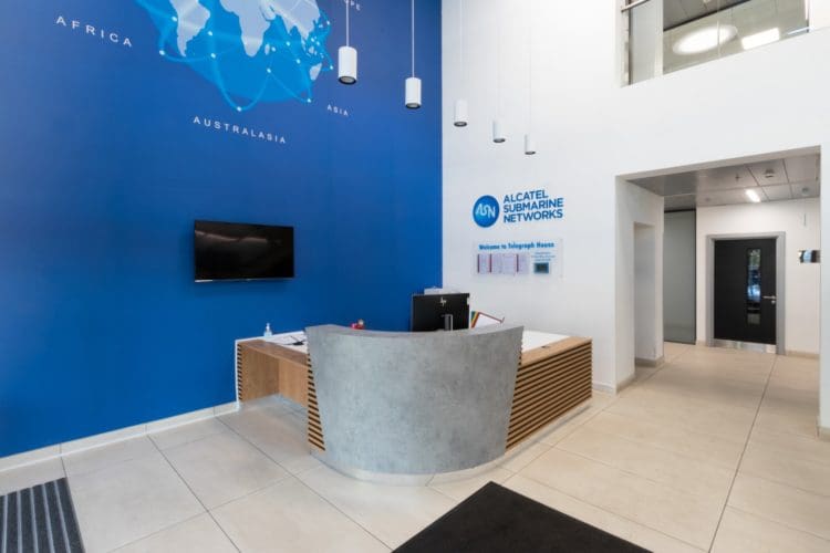 Bespoke office reception desk design with timber slats and concrete.