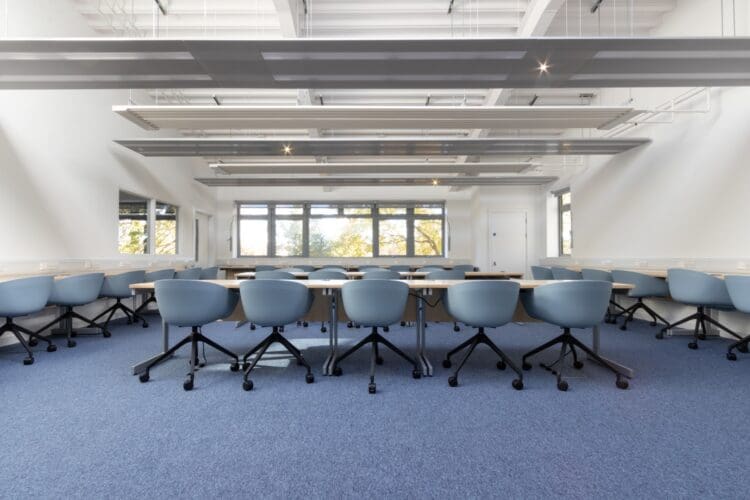 IT classroom interior design project with new school desks and blue swivel chairs.