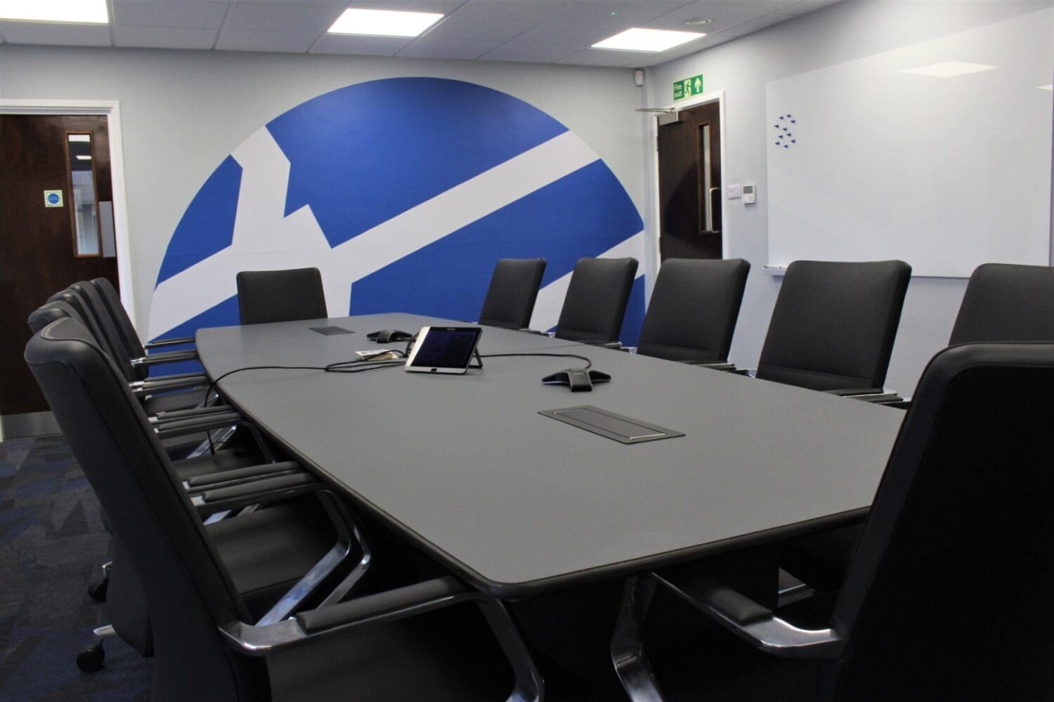 Bespoke boardroom table in corporate office interior design scheme with company logo feature wall behind.