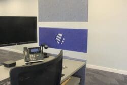 Acoustic panels hung at the end of desks to create division of space in a corporate office.