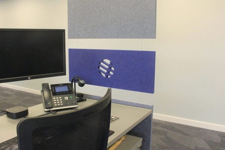 Acoustic panels hung at the end of desks to create division of space in a corporate office.