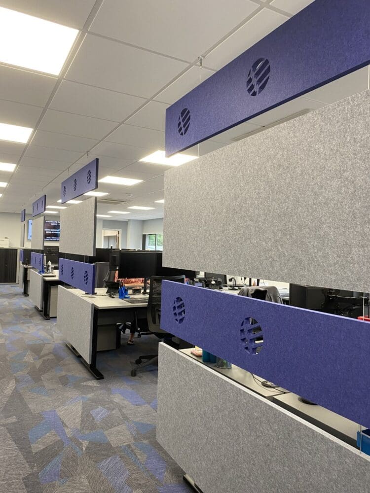 Acoustic panels hung to create a walkway through a large office including the company's branded logo.