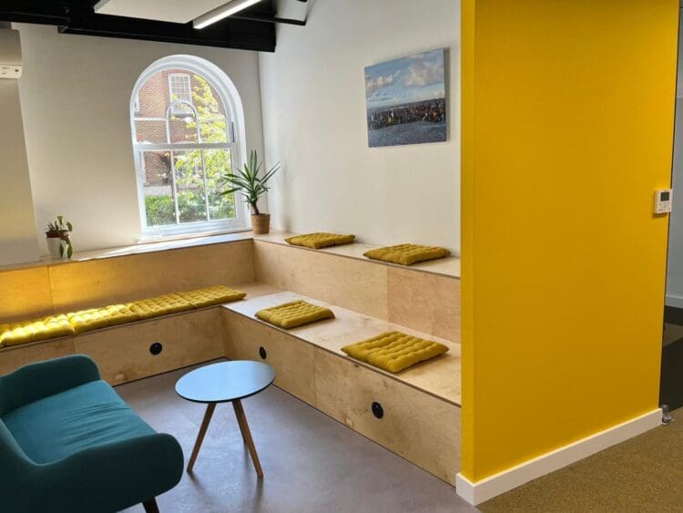 Bleacher seating and sofa with yellow feature wall in office refurbishment London.