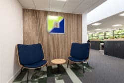 Branded wooden slat feature wall and soft seating in office entrance area.