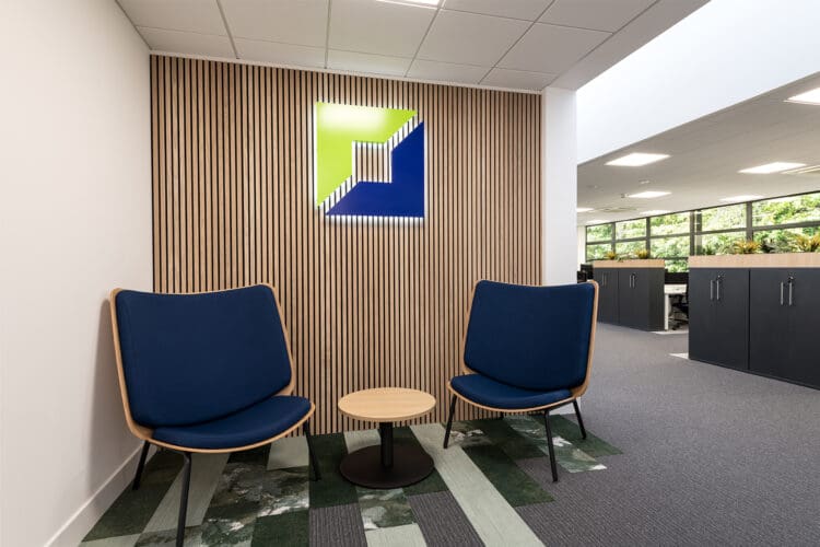 Branded wooden slat feature wall and soft seating in office entrance area.
