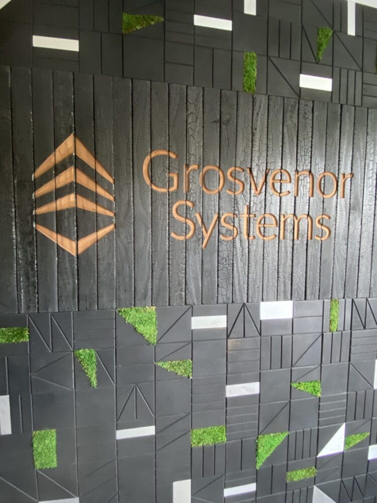 Branded feature wall in charred timber with moss and stainless steel inserts.