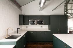Large office tea point with dark green doors and brass hardware.