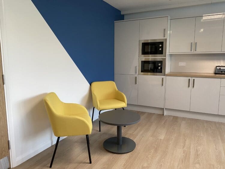 Small breakout area with yellow soft seating in school staffroom refurbishment.