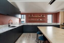 Cool office kitchen design with dark green units and terazzo worktops in London fit out project.