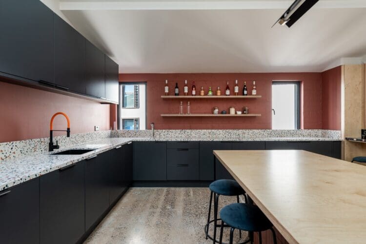 Cool office kitchen design with dark green units and terazzo worktops in London fit out project.