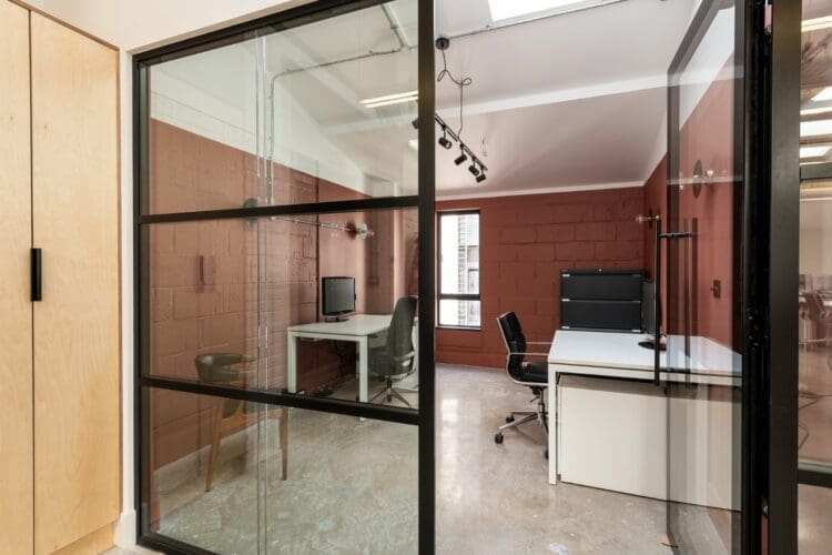 Glazed fronted private office with terracotta walls.