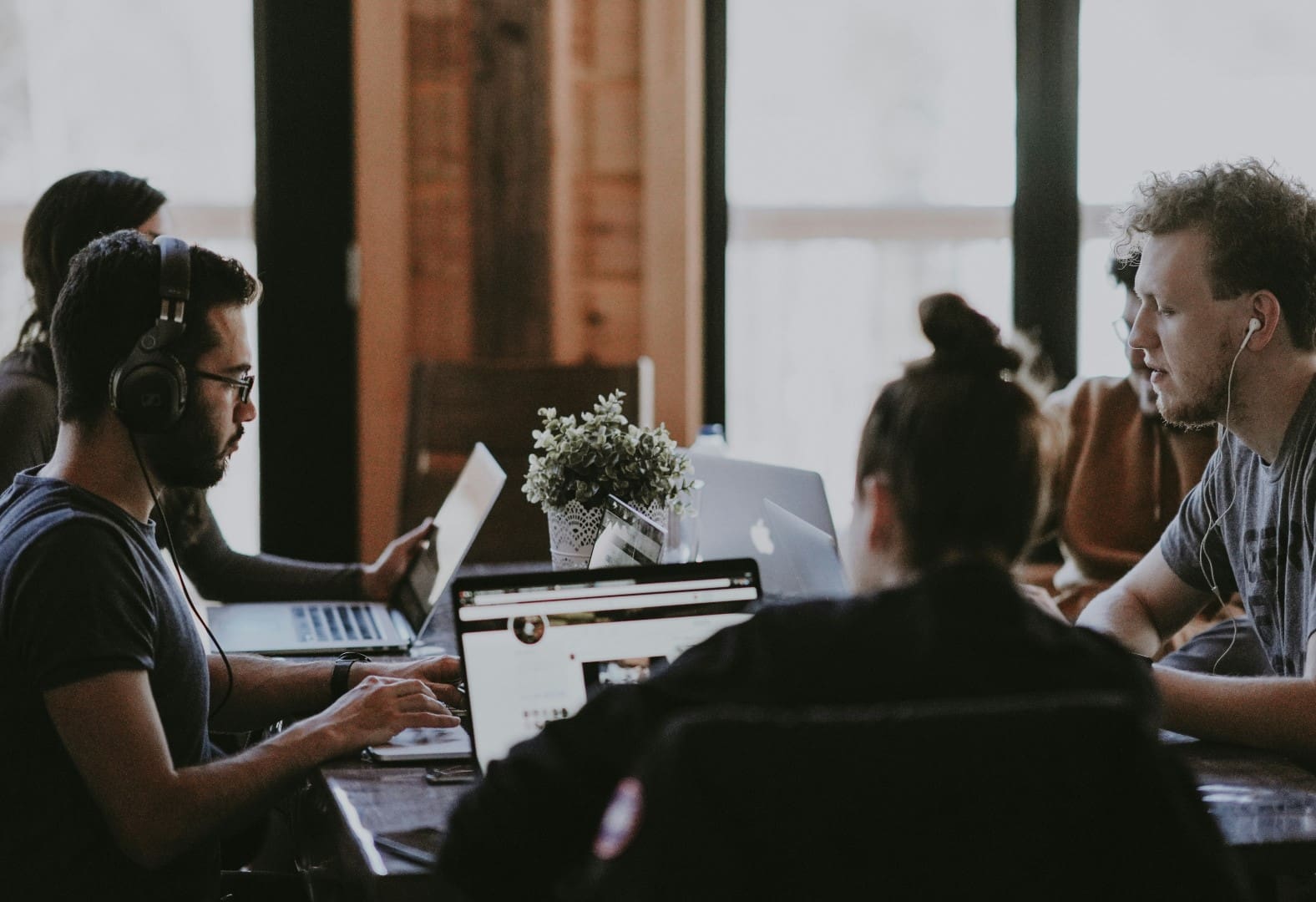 Coworking office set up with colleagues working around meeting table.