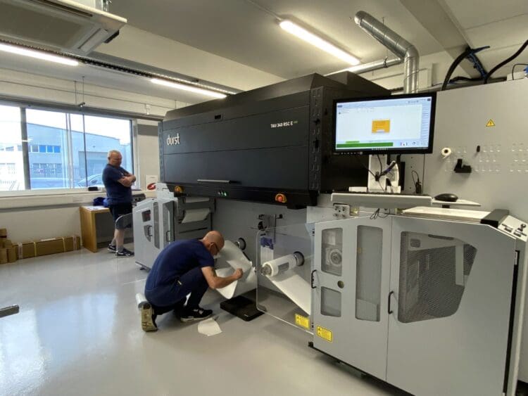 Staff operating printing press machine in industrial fit out project, London.