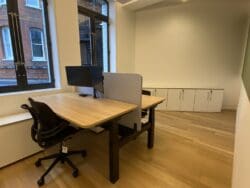 Height adjustable desks in London office refurbishment with grey desk screen.