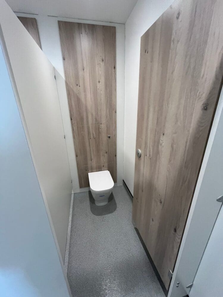 Modern washroom cubicle with timber effect door and panelling.