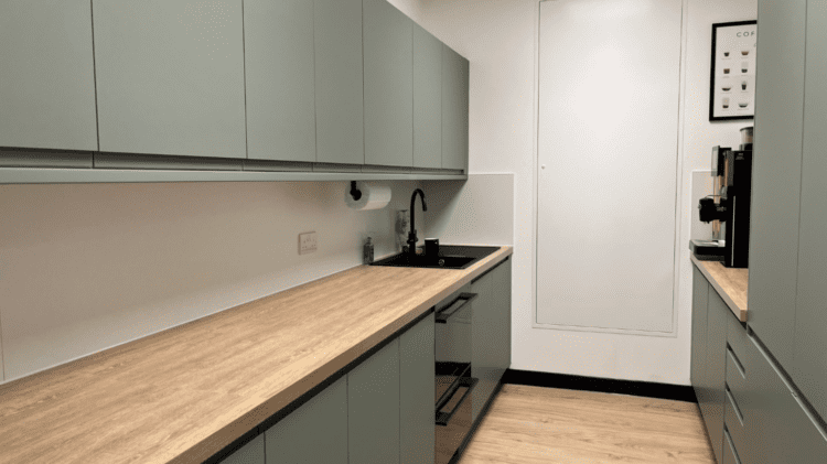 Office tea point refurbishment with sage green units and wood effect worktop.