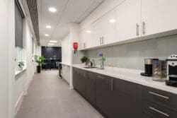 Modern office tea point with gloss cupboards and breakout space.